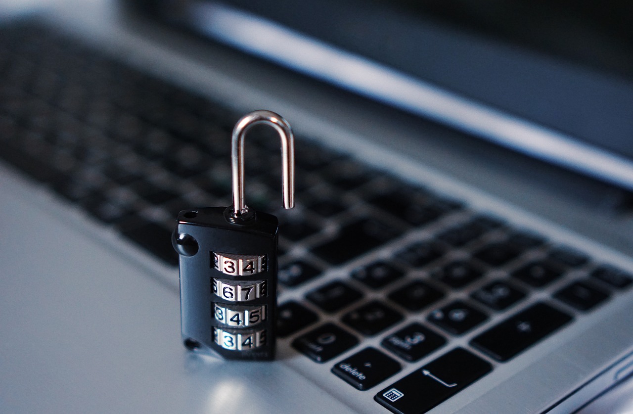 a numerical padlock open, sitting atop a laptop computer