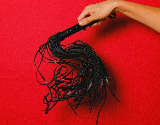 a woman's hand holding a cat-o-nine-tails whip