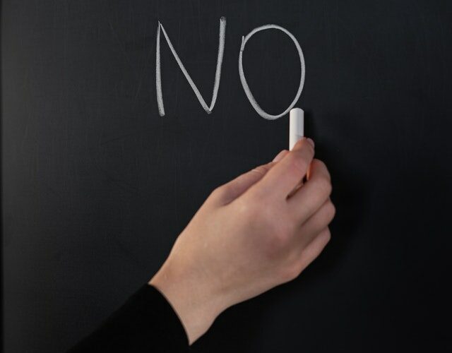 a hand writing "no" on a chalkboard