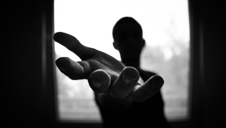 black and white photo of man reaching out his hand